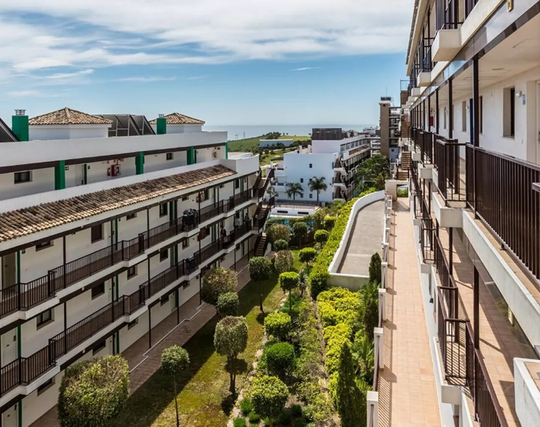 Appartementen met balkons en privéterrassen rond de binnentuin van Ona Valle Romano, met zeezicht in de verte