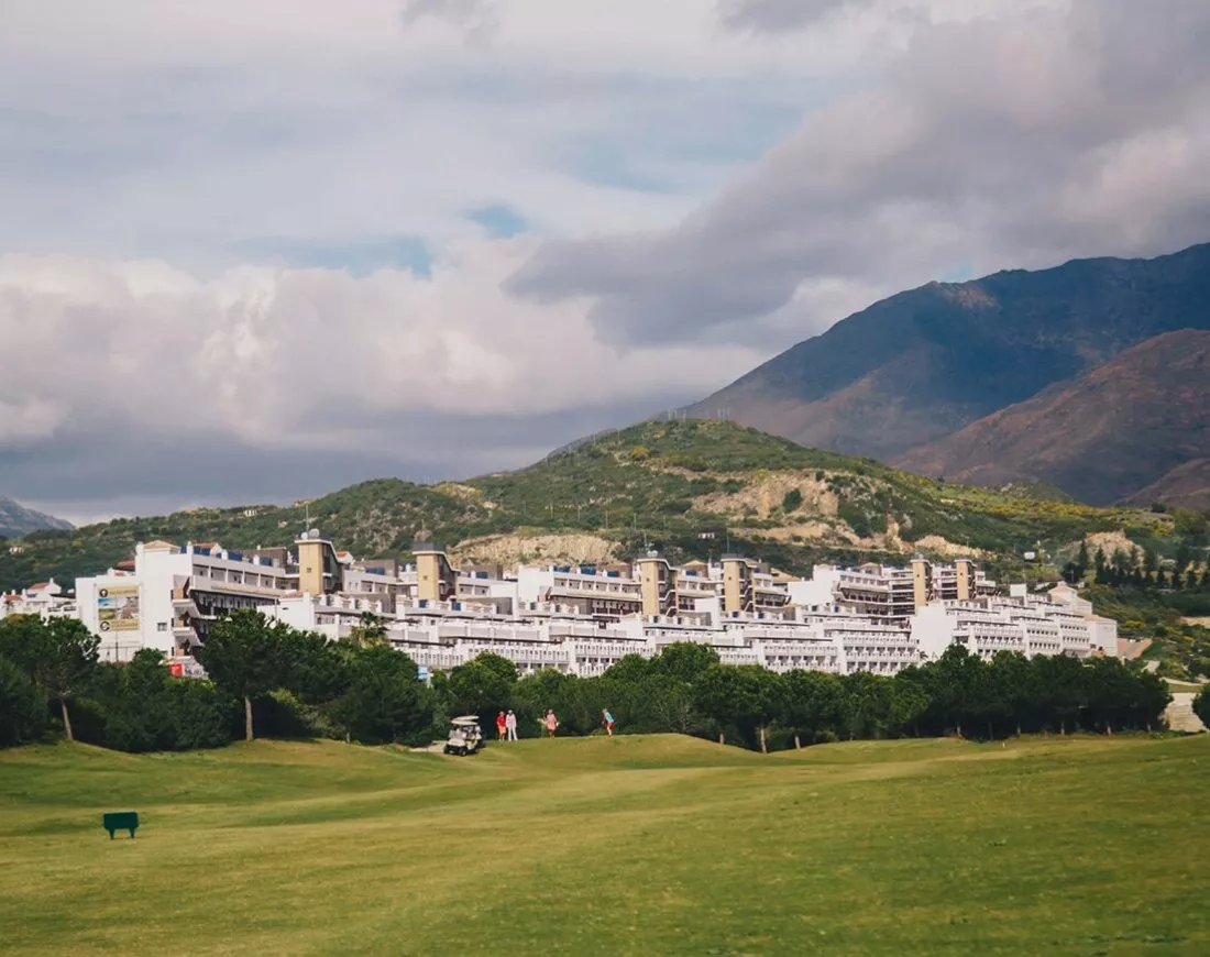 Het complex van Ona Valle Romano tegen de berghelling, met de golfbaan op de voorgrond